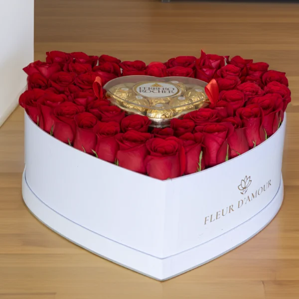 caja en forma de corazón con espuma floral, contiene entre 40 a 45 rosas rojas frescas y una caja de chocolates ferrero en el centro del arreglo. vista de frente