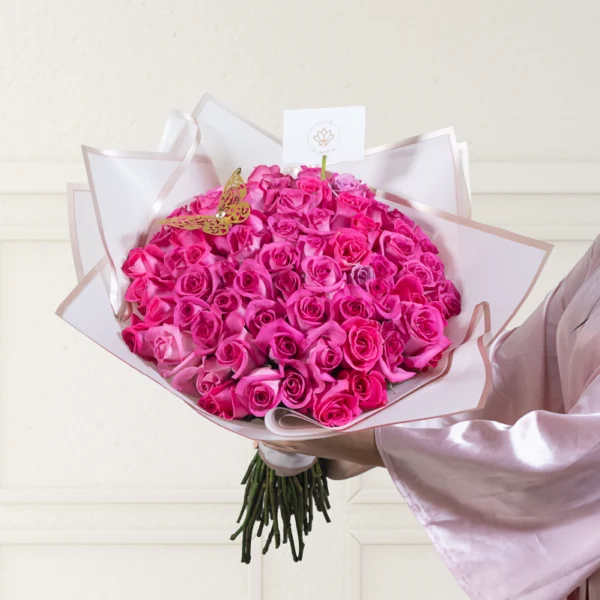 ramo buchón mediano de 75 rosas fucsias con papel coreano rosado que envuelve el ramo, en el ramo encuentras una mariposa dorada y una nota personalizada